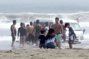 お盆休みの大洗海岸でハイエースを埋める遊びをしている若者たちが撮影される。